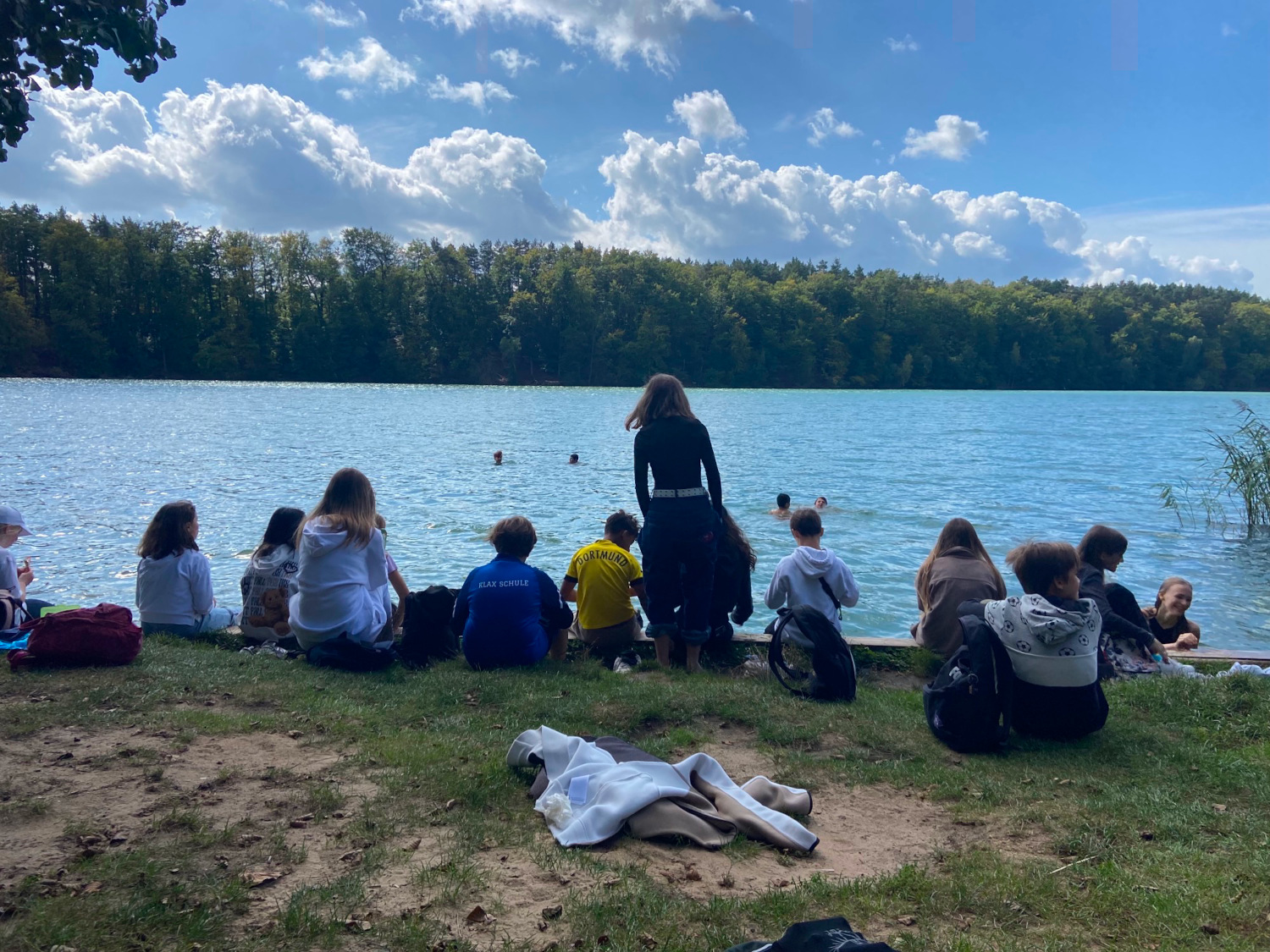 Schülerinnen und Schüler sitzen am See